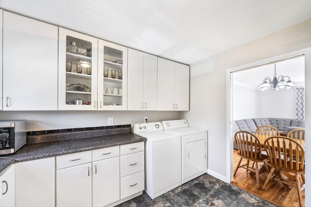 washroom featuring a chandelier, washer and clothes dryer, cabinet space, and baseboards