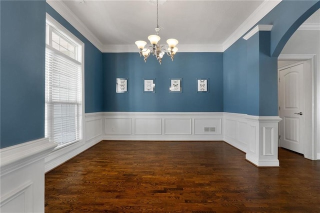 unfurnished dining area featuring dark wood-style floors, a notable chandelier, and ornamental molding