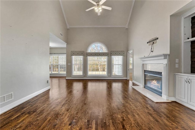 unfurnished living room with baseboards, visible vents, a tile fireplace, dark wood-style flooring, and high vaulted ceiling