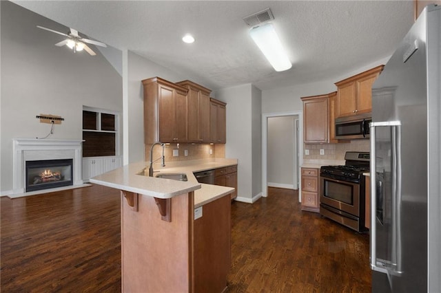 kitchen featuring stainless steel appliances, a breakfast bar, a sink, open floor plan, and light countertops