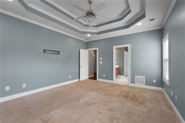 unfurnished bedroom featuring a raised ceiling, visible vents, crown molding, and light carpet