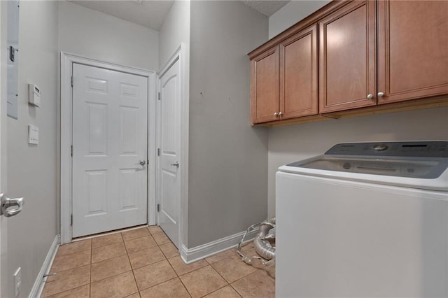 clothes washing area with cabinet space, baseboards, washer / clothes dryer, and light tile patterned flooring