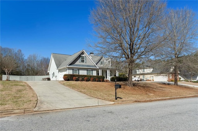 view of front facade with concrete driveway, fence, and a front lawn