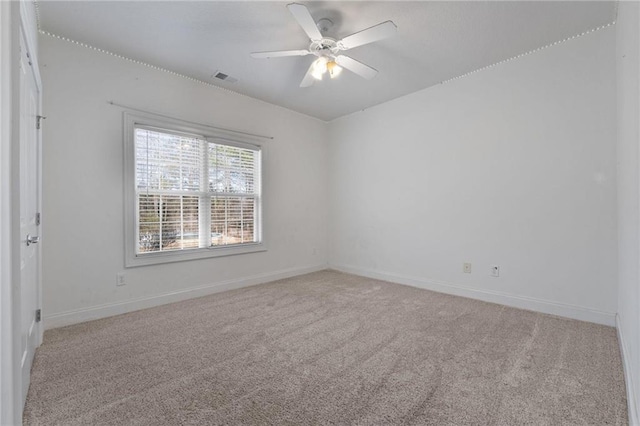 spare room with light colored carpet, visible vents, ceiling fan, and baseboards