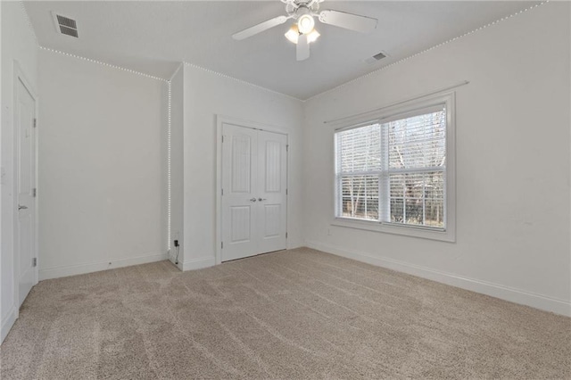 unfurnished bedroom with a ceiling fan, visible vents, light carpet, and baseboards