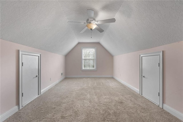 additional living space with light carpet, baseboards, vaulted ceiling, and a textured ceiling