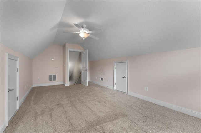 additional living space featuring ceiling fan, lofted ceiling, light carpet, visible vents, and baseboards