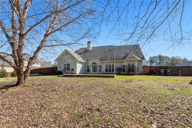 back of property featuring a yard, a chimney, and a fenced backyard