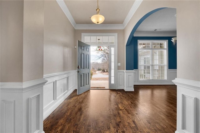 entryway with ornamental molding, arched walkways, dark wood-style flooring, and wainscoting