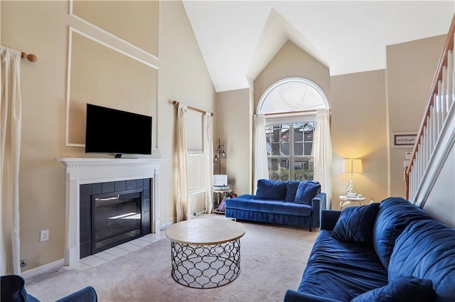 carpeted living room with baseboards, a fireplace, high vaulted ceiling, and stairway