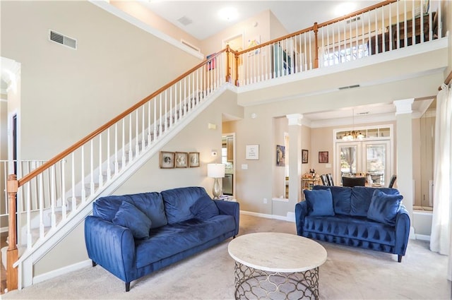 living room with stairway, a high ceiling, baseboards, visible vents, and ornate columns
