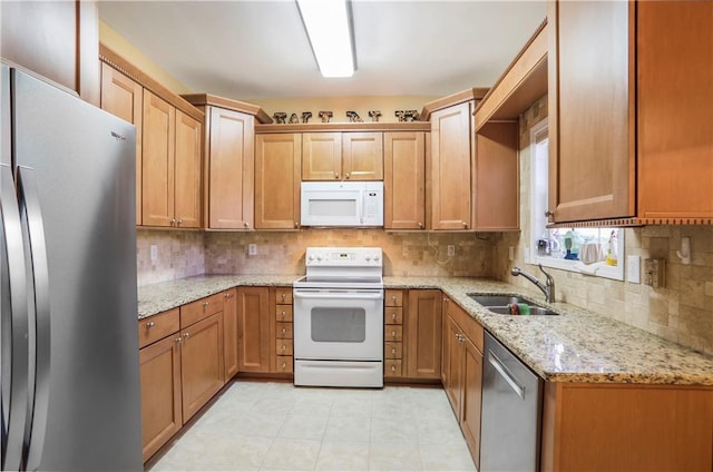 kitchen with decorative backsplash, a sink, stainless steel appliances, and light stone counters