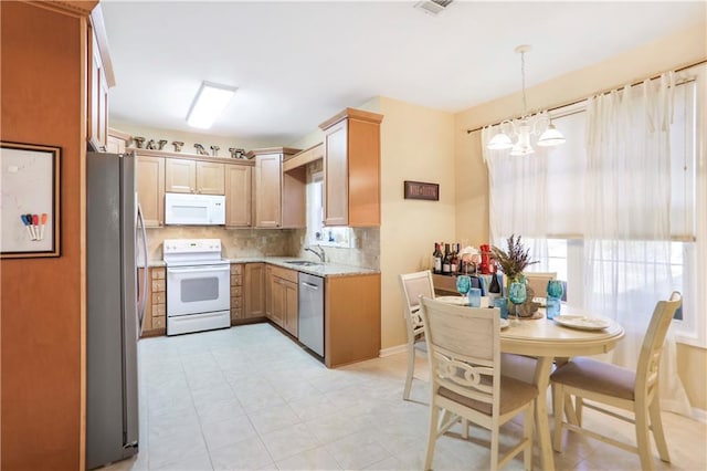 kitchen featuring a healthy amount of sunlight, a chandelier, backsplash, a sink, and appliances with stainless steel finishes