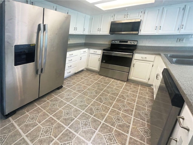 kitchen featuring appliances with stainless steel finishes, sink, white cabinets, and decorative backsplash