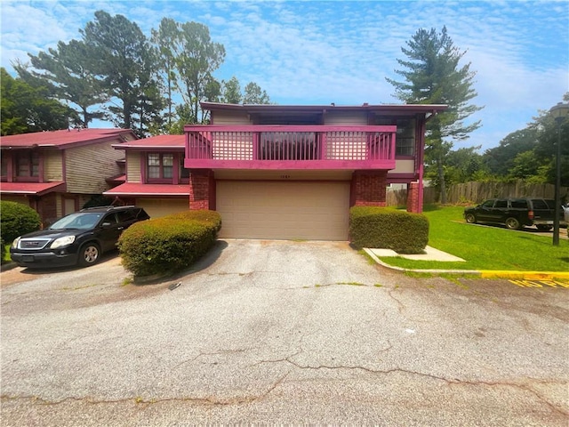 front of property with a garage, a front lawn, and a balcony