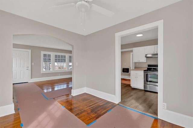 interior space featuring arched walkways, wood finished floors, and baseboards