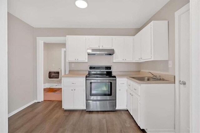 kitchen featuring white cabinets, electric stove, heating unit, light countertops, and under cabinet range hood