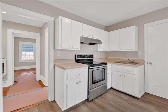 kitchen with under cabinet range hood, a sink, white cabinets, stainless steel range with electric cooktop, and light countertops