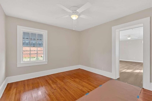 spare room featuring ceiling fan, baseboards, and wood finished floors