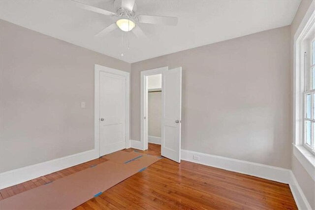 spare room with wood finished floors, a ceiling fan, and baseboards