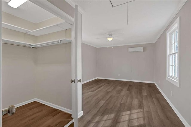 interior space with dark wood-style floors, attic access, baseboards, and a wall mounted air conditioner