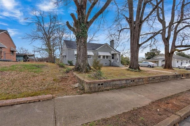 view of front of property featuring concrete driveway, a front lawn, a chimney, and a residential view