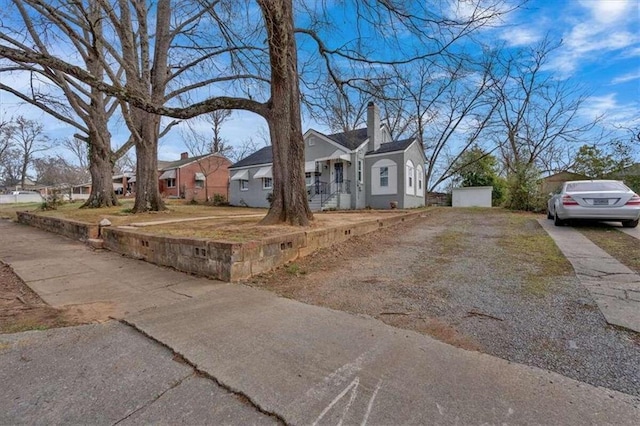 view of front facade with driveway, a chimney, a residential view, and stucco siding