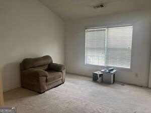 living area featuring light carpet and lofted ceiling