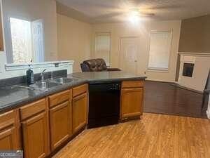 kitchen featuring sink, black dishwasher, and light wood-type flooring