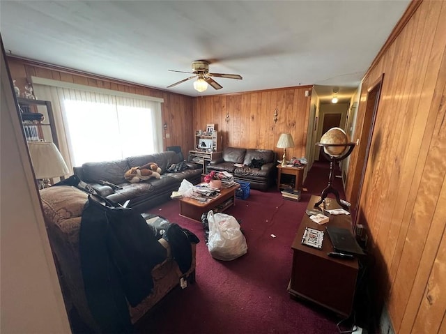 carpeted living room featuring ceiling fan and wood walls