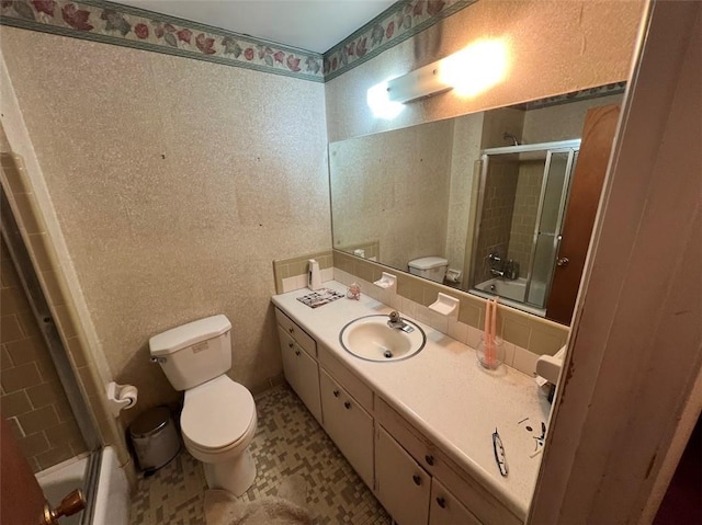 full bathroom with vanity, bath / shower combo with glass door, and toilet