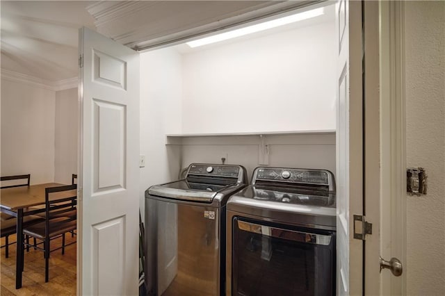 laundry area featuring laundry area, light wood-style flooring, ornamental molding, and washer and dryer