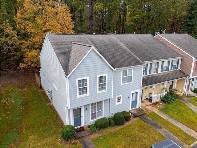 view of property with roof with shingles and a front yard