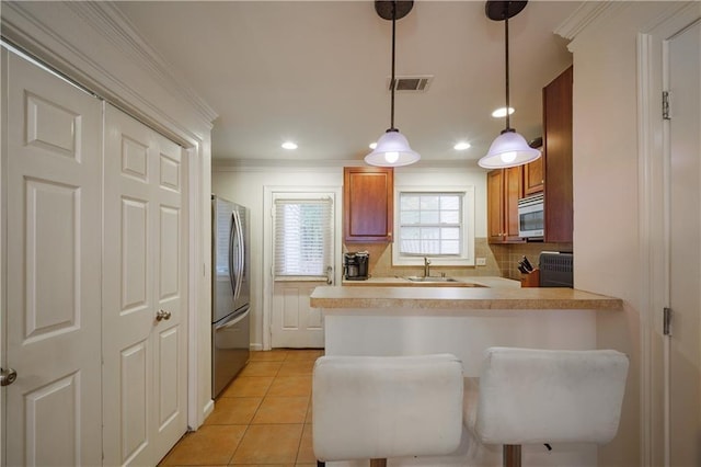 kitchen featuring a peninsula, appliances with stainless steel finishes, light countertops, and a kitchen breakfast bar