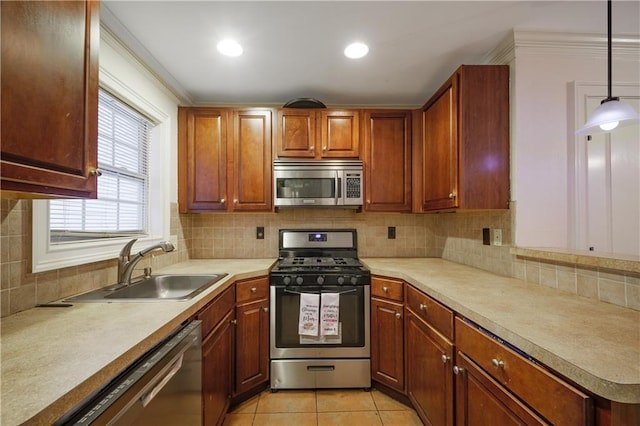 kitchen with appliances with stainless steel finishes, light countertops, a sink, and decorative light fixtures