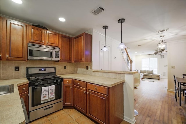 kitchen featuring light countertops, appliances with stainless steel finishes, a peninsula, and hanging light fixtures