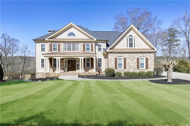 view of front facade featuring brick siding, stone siding, covered porch, and a front lawn