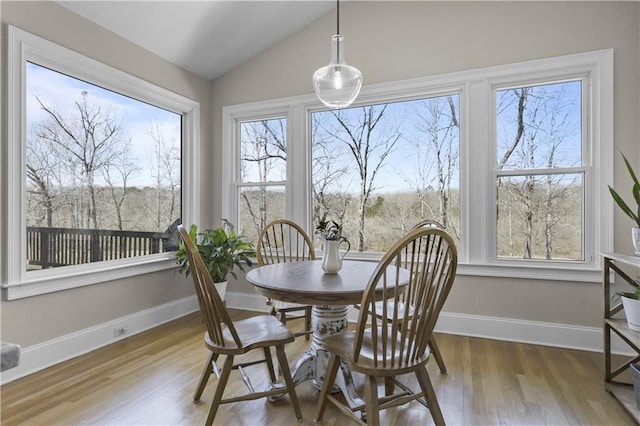 dining room with a wealth of natural light, baseboards, lofted ceiling, and wood finished floors