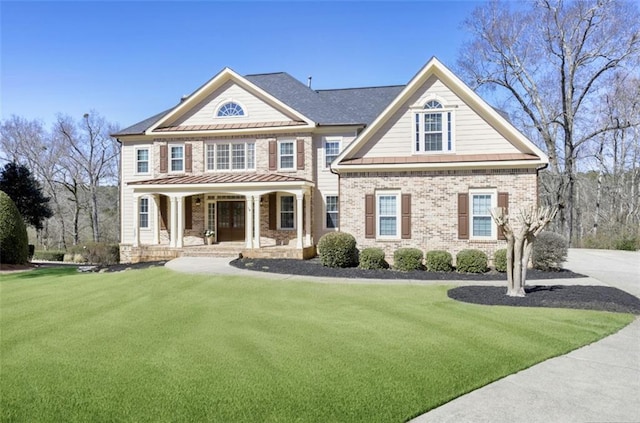 view of front of house featuring brick siding, covered porch, and a front lawn