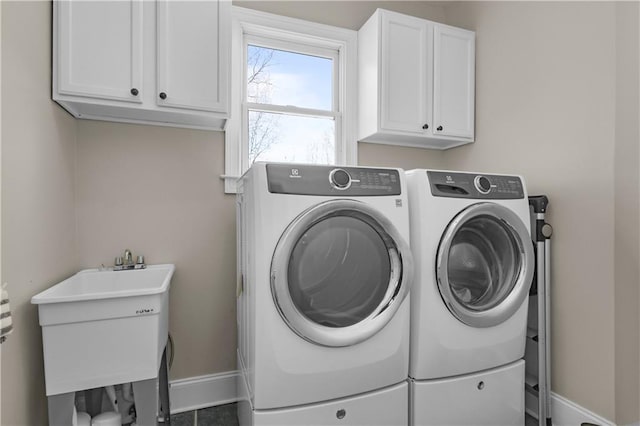 laundry room with cabinet space, washer and dryer, baseboards, and a sink