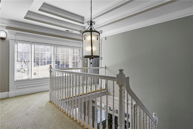 stairs featuring baseboards, a notable chandelier, crown molding, a raised ceiling, and carpet flooring