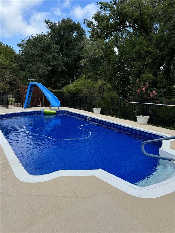 view of swimming pool featuring a patio, a fenced backyard, a fenced in pool, and a water slide