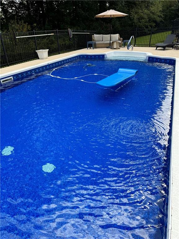 view of swimming pool featuring an outdoor living space, a fenced in pool, and fence