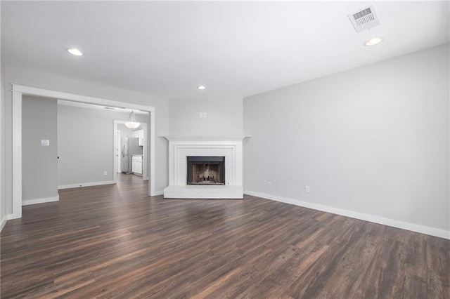 unfurnished living room featuring dark hardwood / wood-style flooring and a brick fireplace