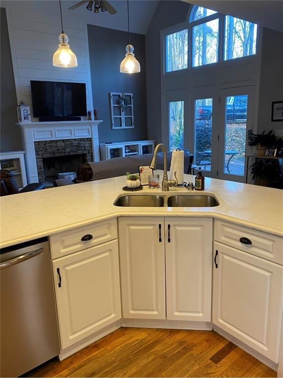 180 Hightower Lake Trl, Ball Ground, GA 30107 - kitchen featuring vaulted ceiling, light wood-type flooring, a stone fireplace, light countertops, and pendant lighting