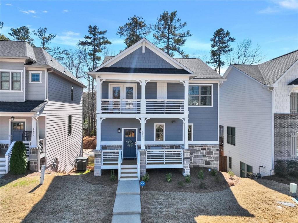 view of front of house featuring cooling unit, a balcony, covered porch, stone siding, and roof with shingles