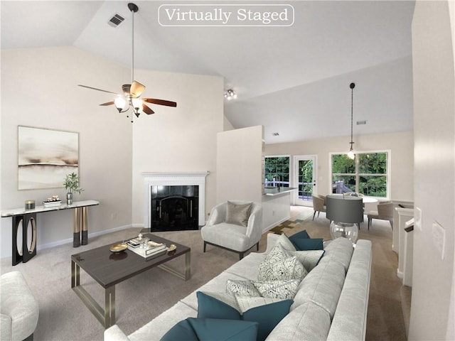 living room with ceiling fan, light colored carpet, a fireplace, and vaulted ceiling