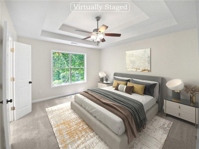 bedroom featuring ceiling fan, light carpet, and a tray ceiling