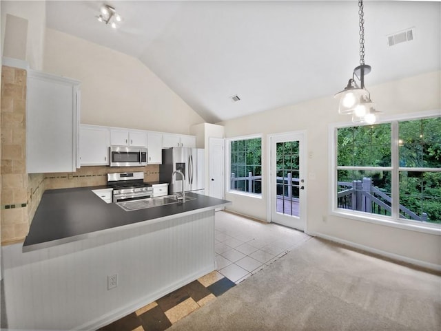 kitchen with pendant lighting, kitchen peninsula, appliances with stainless steel finishes, tasteful backsplash, and white cabinetry