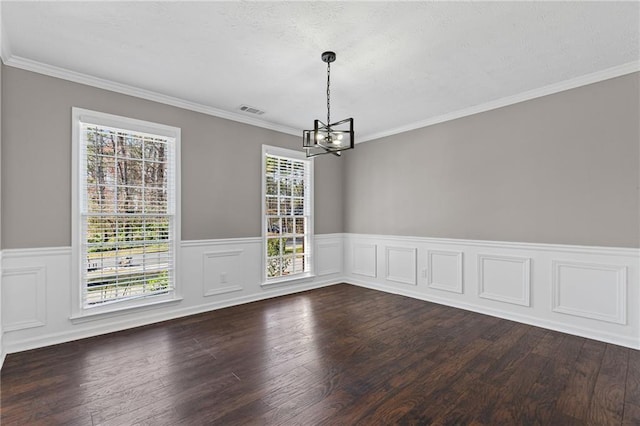 spare room with a notable chandelier, visible vents, crown molding, and dark wood-style flooring